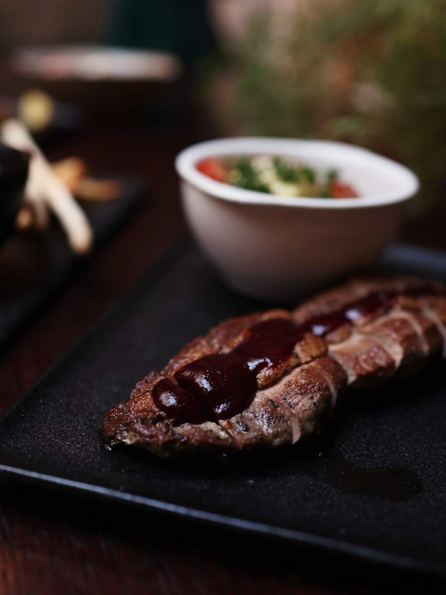 A wood-fired dish on a dark plate, charred at the edges.