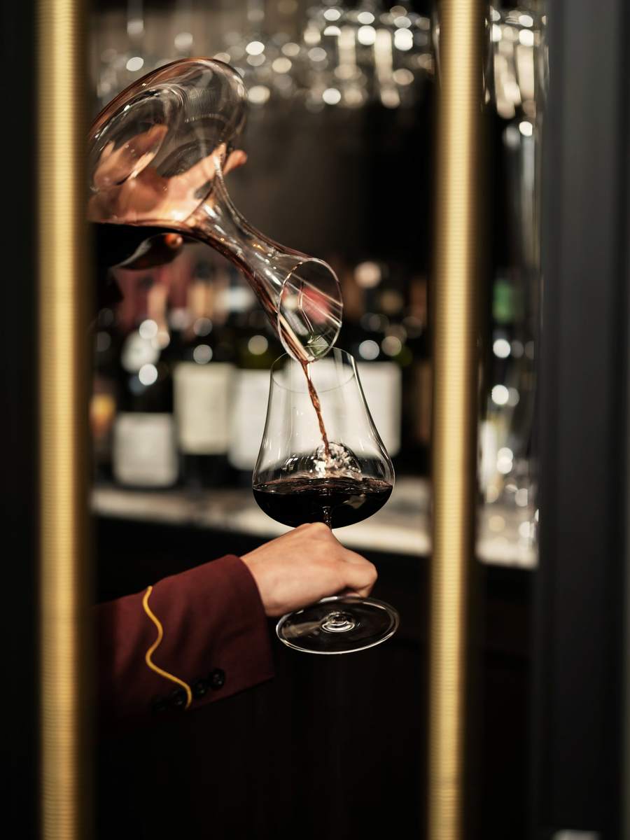 A glass of wine being poured in low light.